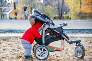 un pequeño niño toma su juguetes fuera de el paseante foto