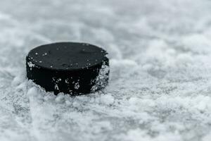 hockey puck lies on the snow close-up photo