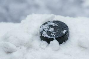 hockey puck lies on the snow close-up photo