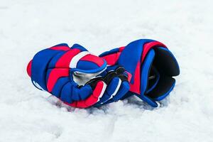 colored hockey player gloves lie on the snow photo