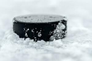 hockey puck lies on the snow close-up photo