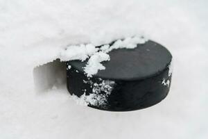 hockey puck lies on the snow close-up photo