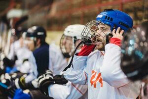 hockey jugador mantiene gritos su equipo sentado en el banco foto