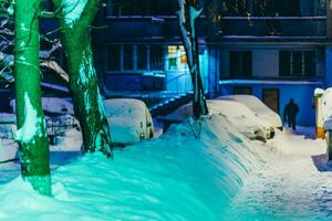 cars stand in the yard in the evening covered with snow photo