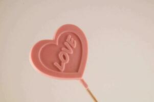 a pink heart shaped lollipop with the word love written on it photo