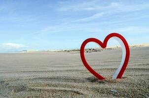 a red heart shaped object in the sand photo