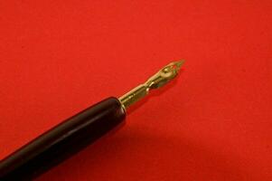 a fountain pen laying on top of a red surface photo