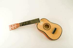 a small wooden guitar on a white surface photo