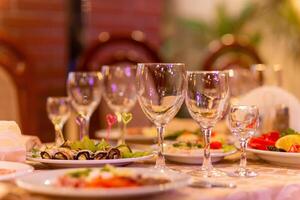 servido festivo mesa con aperitivos, anteojos, anteojos, cuchillería y servilletas para un banquete foto