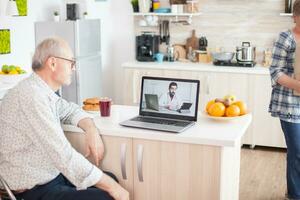 video conference with doctor using laptop in kitchen. Online health consultation for elderly people drugs ilness advice on symptoms, physician telemedicine webcam. Medical care internet chat photo