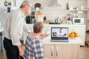 Senior woman showing pills bottle to doctor during video telemedicine conference. Online health consultation for elderly people drugs ilness advice on symptoms, physician telemedicine webcam. Medical care internet chat photo