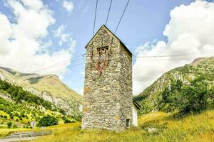 a stone tower in the mountains with power lines photo