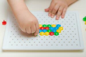 the baby plays with a mosaic sitting at a table photo