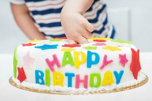 pequeño bebé toques su cumpleaños pastel cuales mentiras en el mesa foto