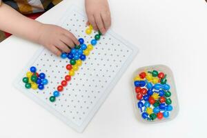 the baby plays with a mosaic sitting at a table photo