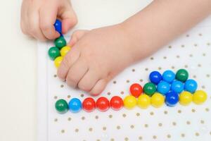 the baby plays with a mosaic sitting at a table photo