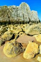 a rock formation on the beach with a blue sky photo