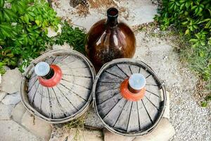 two wine bottles and a wooden barrel sitting on top of a stone photo