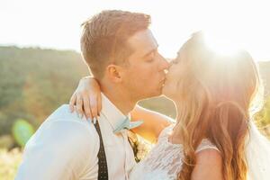 the bride and groom kissing at sunset photo