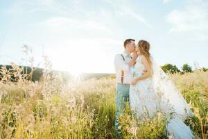 the bride and groom kissing at sunset photo