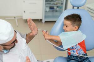 el dentista obras de teatro con un pequeño paciente entonces ese él es no temeroso a tratar su dientes foto