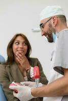 the dentist shows the patient on the example of a human jaw, how teeth are arranged in the mouth photo