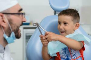 the dentist plays with a small patient so that he is not afraid to treat his teeth photo