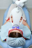 the patient undergoes a procedure for teeth whitening with an ultraviolet lamp photo