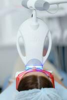 the patient undergoes a procedure for teeth whitening with an ultraviolet lamp photo