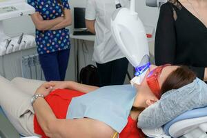 the patient undergoes a procedure for teeth whitening with an ultraviolet lamp photo