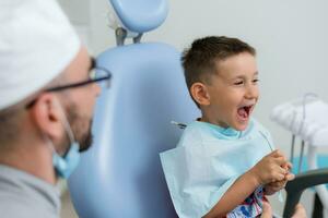 el dentista obras de teatro con un pequeño paciente entonces ese él es no temeroso a tratar su dientes foto
