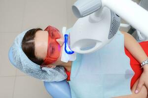 the patient undergoes a procedure for teeth whitening with an ultraviolet lamp photo