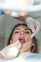 doctor orthodontist examines the oral cavity of a beautiful patient photo