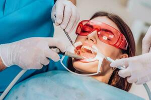 doctor orthodontist performs a procedure for cleaning teeth photo
