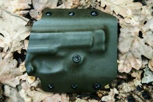 objective holster shooting on dry leaves in the forest photo