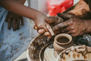 master of pottery teaches a little girl how to keep fingers photo