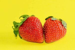 two strawberries on a yellow background photo