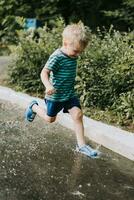 little boy jumping in a puddle in summer photo