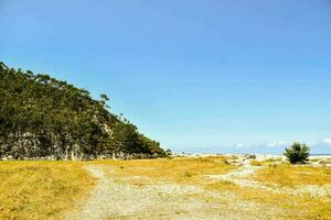 a dirt road leads to a beach and a mountain photo