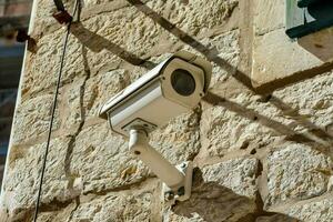 a security camera mounted on a stone wall photo