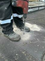 construcción trabajador manejo un perforar a hacer un agujero en un hormigón piso. foto