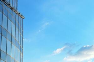 Structural glass wall reflecting blue sky. Abstract modern architecture fragment photo