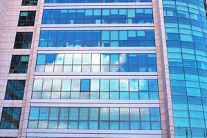 Structural glass wall reflecting blue sky. Abstract modern architecture fragment photo