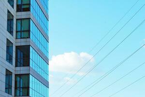 Structural glass wall reflecting blue sky. Abstract modern architecture fragment photo
