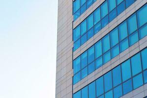 Structural glass wall reflecting blue sky. Abstract modern architecture fragment photo