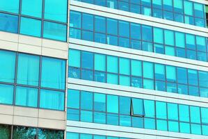 Structural glass wall reflecting blue sky. Abstract modern architecture fragment photo