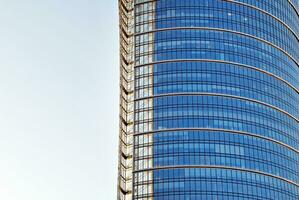 Structural glass wall reflecting blue sky. Abstract modern architecture fragment. photo