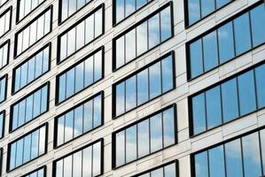 Structural glass wall reflecting blue sky. Abstract modern architecture fragment photo