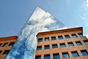 Structural glass wall reflecting blue sky. Abstract modern architecture fragment. photo