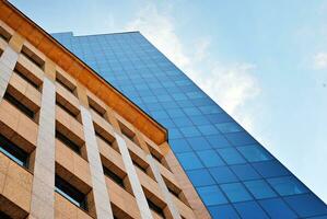 Structural glass wall reflecting blue sky. Abstract modern architecture fragment. photo